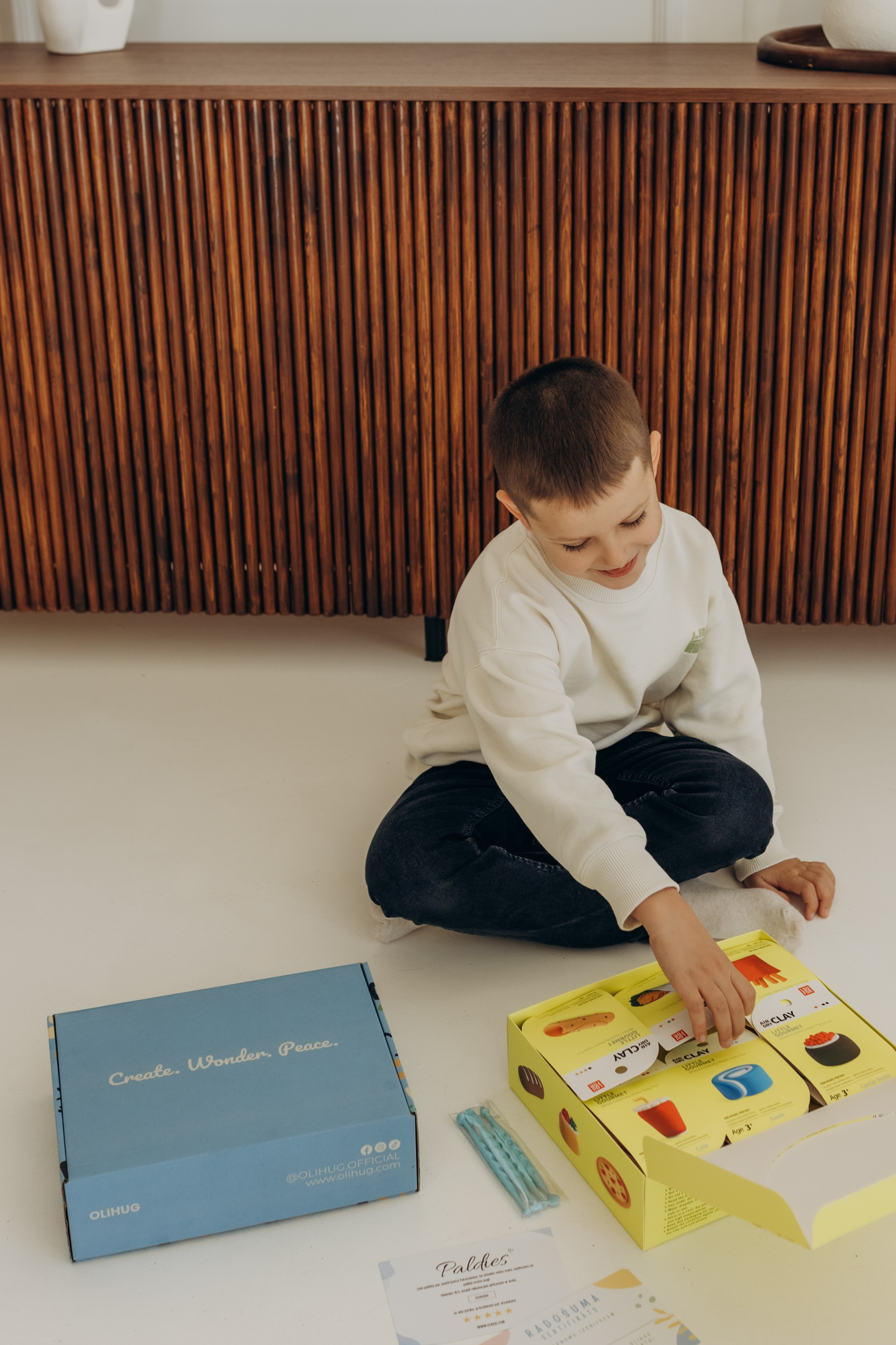 Child playing with OLIHUG air-dry clay kit, opening creative box and shaping colorful modeling clay for screen-free educational play